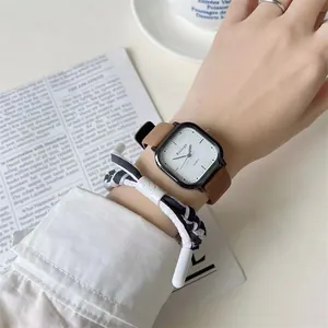 Nahaufnahme einer quadratischen Quarzuhr mit braunem Lederarmband und geflochtenem Band