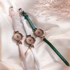 Nahaufnahme minimalistischer Damenquarzuhren mit bunten Lederarmbändern auf Seidenstoff