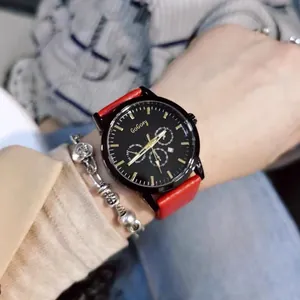 Detail of black dial quartz watch with red leather strap and small weekday sub-dial display