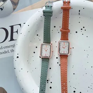Detailopname van rechthoekige quartzhorloges met groene en oranje lederen bandjes