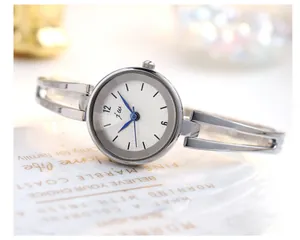 Detalle macro de reloj brazalete plateado con esfera blanca texturizada y agujas azules