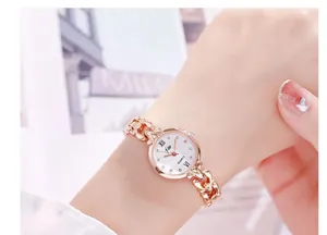 Détail d'une montre à quartz en or rose avec bracelet chaîne et cadran romain blanc