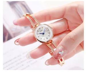 Detalle de reloj de pulsera en oro rosa con esfera blanca y agujas azules para mujer