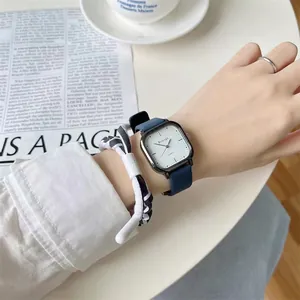 Nahaufnahme einer quadratischen Quarzuhr mit blauem Lederarmband am Handgelenk