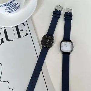 Nahaufnahme von quadratischen Quarzuhren mit Lederarmbändern neben einer Kaffeetasse