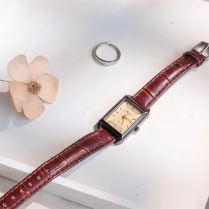 Close-up of rectangular quartz watch with roman numerals and brown leather strap