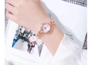 Gros plan d'une montre bracelet en or rose avec cadran rose au poignet d'un mannequin