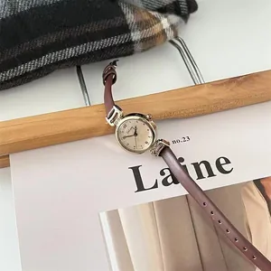 Detalle de reloj vintage para mujer con correa de cuero marrón y esfera dorada elegante
