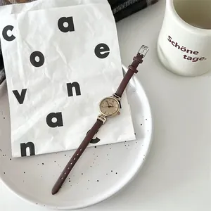 Primer plano de reloj de cuarzo retro para mujer con correa de cuero marrón y esfera dorada