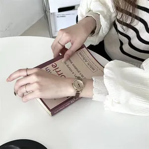 Reloj retro pequeño dorado con correa de cuero marrón y anillos minimalistas