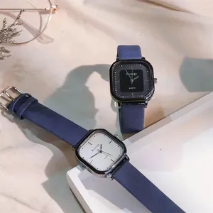 Detailaufnahme quadratischer Quarzuhren mit dunkelblauen Armbändern auf beigem Stoff