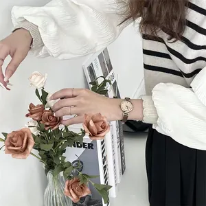 Primer plano de reloj de cuarzo vintage dorado para mujer con correa de cuero marrón fina