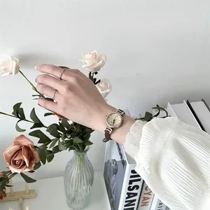 Primer plano de un reloj retro para mujer con correa de cuero marrón y esfera dorada fina