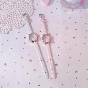 Detail of rose gold cat-ear watches with white and pink leather straps on pink background