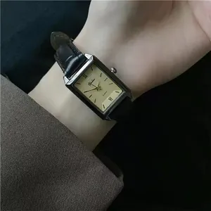 Detail of rectangular quartz watch with black leather strap worn on wrist for a chic look