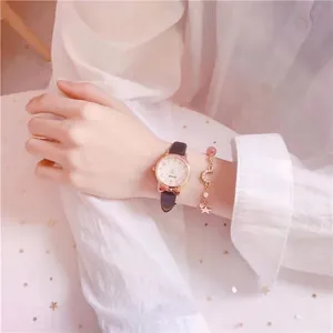 Close-up of rose gold watch with brown leather strap and moon star charm bracelet