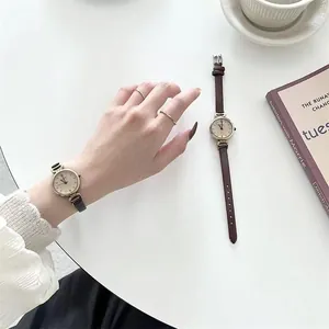 Primer plano de un reloj de cuarzo minimalista para mujer con correa de cuero marrón y caja dorada
