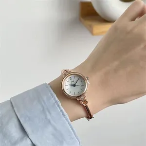 Detail einer Damenuhr in Roségold mit Kristallbesatz und schmalem Metallarmband