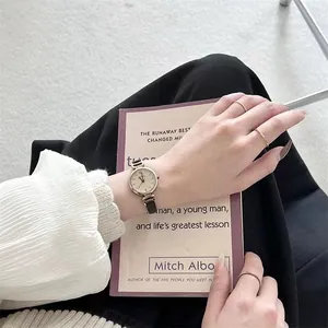 Detalle de un reloj de cuarzo vintage para mujer con esfera dorada y correa de cuero
