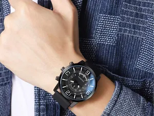 Detail of a men's matte black sports watch with silicone strap on a blue suit arm