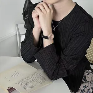 Detail of rose gold quartz watch styled with black pleated top and minimalist jewelry