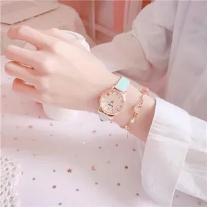 Close-up of a mint green leather watch featuring gold cat-ear case and a pearl charm bracelet