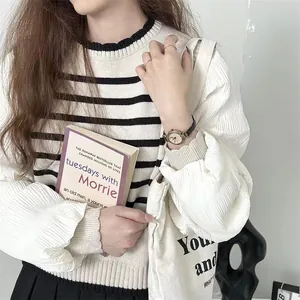 Detalle de un suéter de punto a rayas con elegantes mangas plisadas blancas suaves