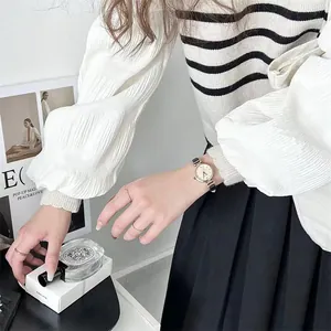 Elegante reloj de cuarzo en oro rosa con correa fina de cuero negro en la muñeca