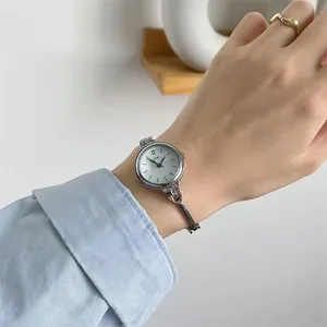 Nahaufnahme einer silbernen Armbanduhr für Damen mit weißem Zifferblatt und Diamantakzenten
