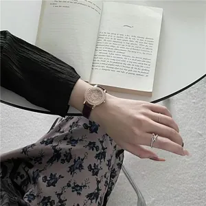 Close-up of rose gold starry watch with leather strap and sparkling crystal bezel