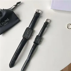 Detail of rectangular couple quartz watches with black leather straps and gold hands
