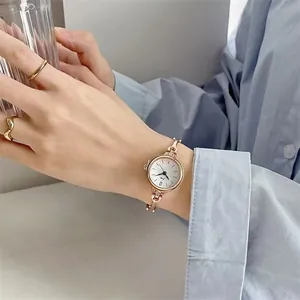 Detail einer roségoldenen Quarzuhr mit Schmuckarmband und Diamanten am Handgelenk