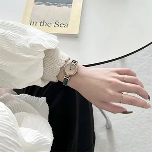 Primer plano de reloj vintage para mujer con esfera pequeña dorada y correa de cuero verde