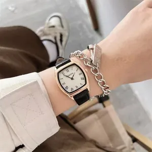 Retro tonneau horloge met zwarte lederen band en gestapelde zilveren kettingarmband om pols
