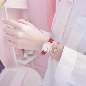 Close-up of red leather watch with cat-ear case paired with a gold star charm bracelet
