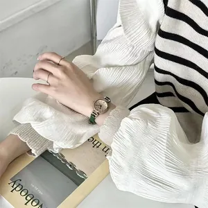 Primer plano de un reloj de cuarzo vintage para mujer con correa de cuero verde en la muñeca
