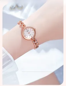 Détail macro du bracelet à maillons cœur en or rose et du cadran blanc de montre quartz