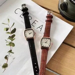 Detailweergave van vintage horloges met lederen bandjes op een minimalistische houten tafel
