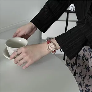 Detail of elegant women's watch with red leather strap and rhinestone bezel on wrist