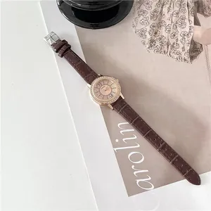 Detail of rose gold starry watch with crystal bezel and brown crocodile leather strap