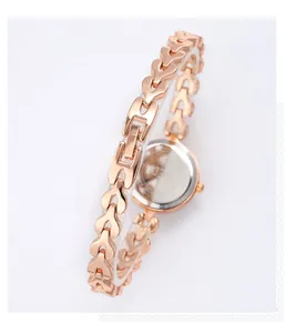 Détail d'une montre chaîne en or rose avec maillons en cœur et fond en acier inoxydable gravé