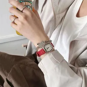 Detail van het vintage tonneau-horloge met rode lederen band en zilveren armbandset
