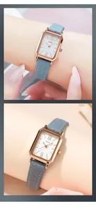 Détail de montre rectangulaire en or rose avec bracelet en cuir bleu foncé et chiffres romains