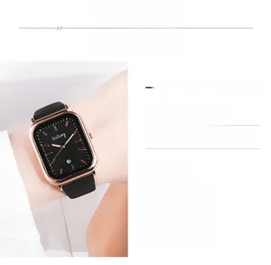 Détail de montre carrée en or rose avec bracelet silicone noir et guichet de date
