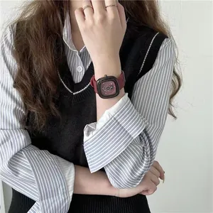 Detail van vierkant bordeauxrood horloge met zwarte kast om de pols gedragen