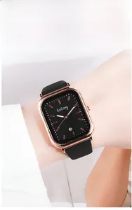 Détail d'une montre rectangulaire or rose avec cadran noir et affichage de la date
