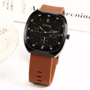 Detail of square black dial with gold markers and brown perforated silicone watch strap