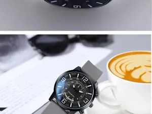 Fashionable large dial watch with grey silicone strap next to a coffee cup and sunglasses
