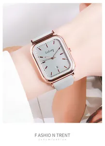Détail d'une montre carrée en or rose avec bracelet silicone gris et dateur