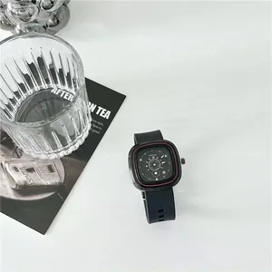 Close-up van een minimalistisch zwart vierkant horloge met siliconen band en rode details